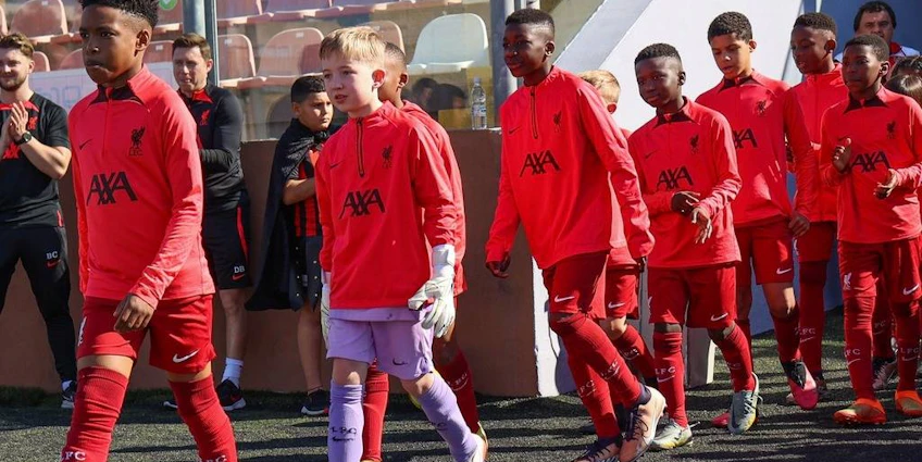 Młodzieżowa drużyna piłkarska w czerwonych strojach wchodzi na boisko na U10 KHS Cup