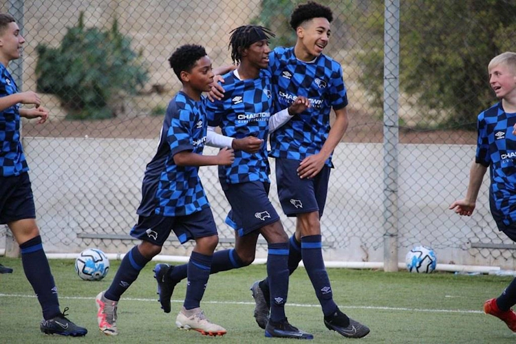 Kék-fekete csíkos U13-as fiatalok gólt ünnepelnek a pályán