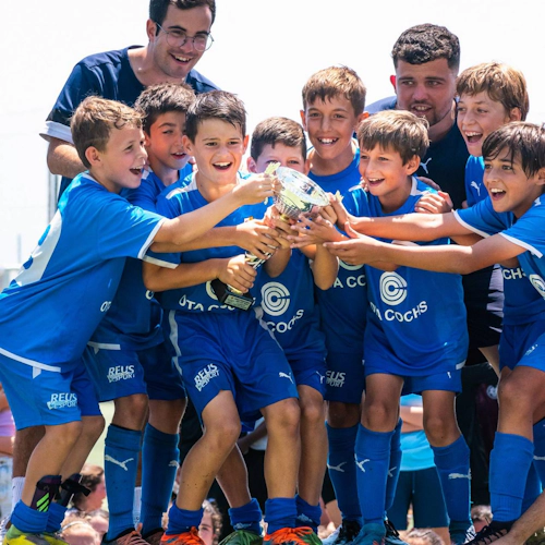 Ungdomsfotballag i blå drakter holder et trofé i turneringen