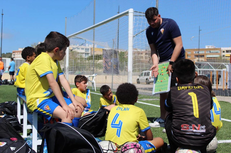 Trener lærer barn på Sun Esei Cup fotballturnering på banen