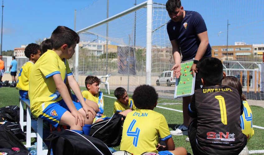 Trainer lehrt Kinder beim Sun Esei Cup Fußballturnier auf dem Feld