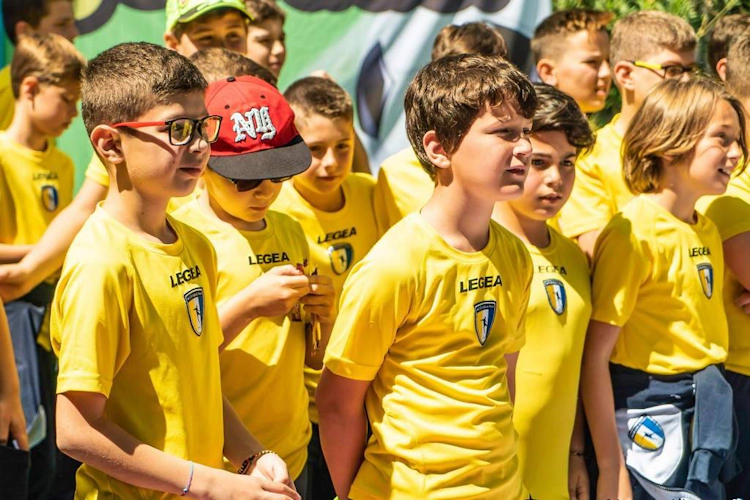 Fiatal labdarúgók csoportja sárga egyenruhában figyelmesen hallgat egy eseményen