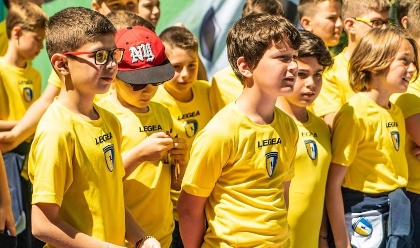 Grupo de jovens jogadores de futebol em uniformes amarelos ouvindo atentamente durante um evento