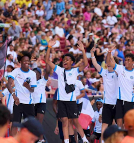 Glade unge fodboldspillere fejrer på stadion med MADCUP flag