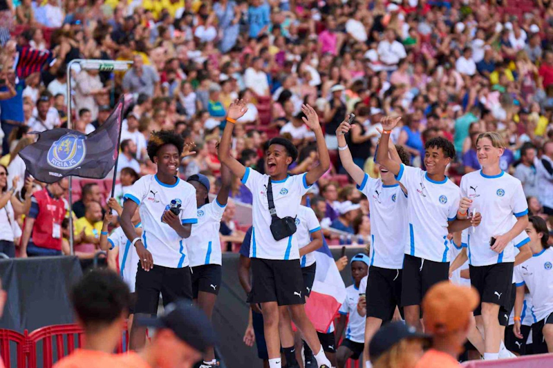 Jóvenes futbolistas alegres celebrando en estadio con bandera MADCUP