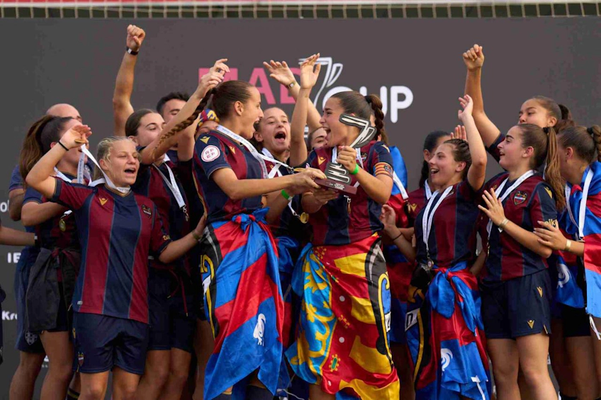 Female football team celebrating with trophy at MADCUP tournament