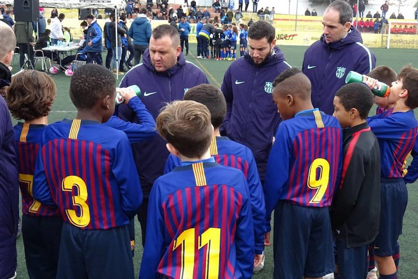 Treinador de futebol discutindo estratégia com equipe juvenil no torneio Torneo Promises