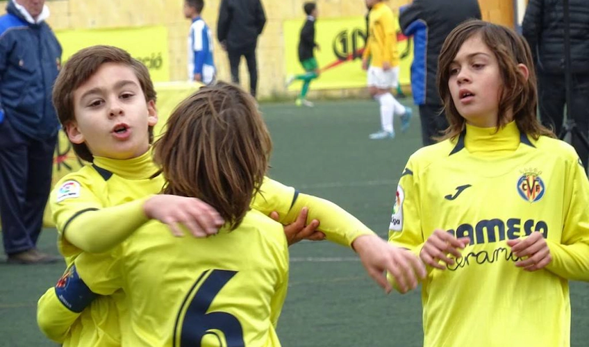 Niños en camisetas amarillas celebrando un gol en el torneo Torneo Promises