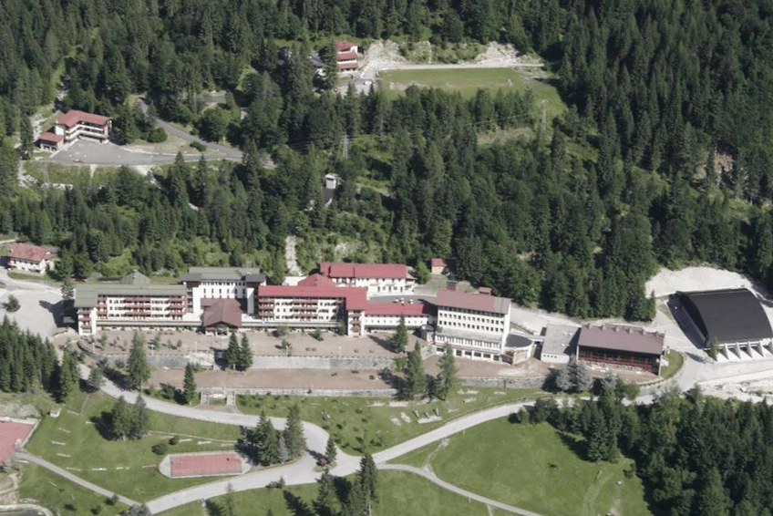 Semesteranläggning i Dolomiterna, Italien, omgiven av tät skog.