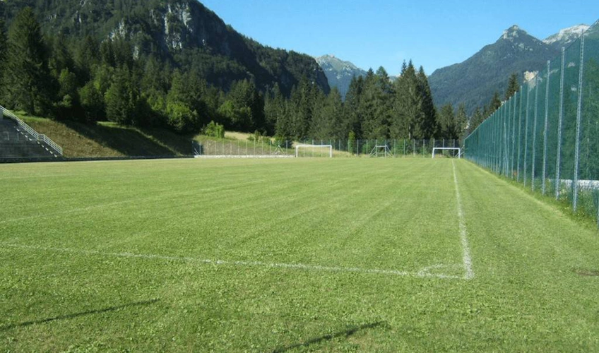 Teren de fotbal Dolomites cu un peisaj montan în fundal
