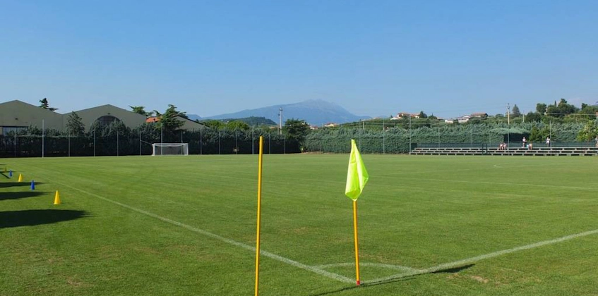 Leeg voetbalveld op het Grand Prix Veronello Summer Trophy-toernooi, met groen en bergen op de achtergrond.