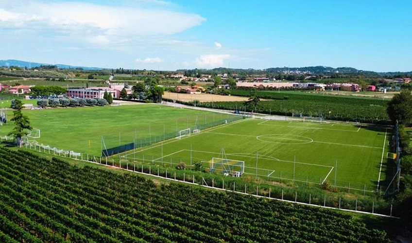 Veronello fodboldbane med grønt græs mod en landlig baggrund