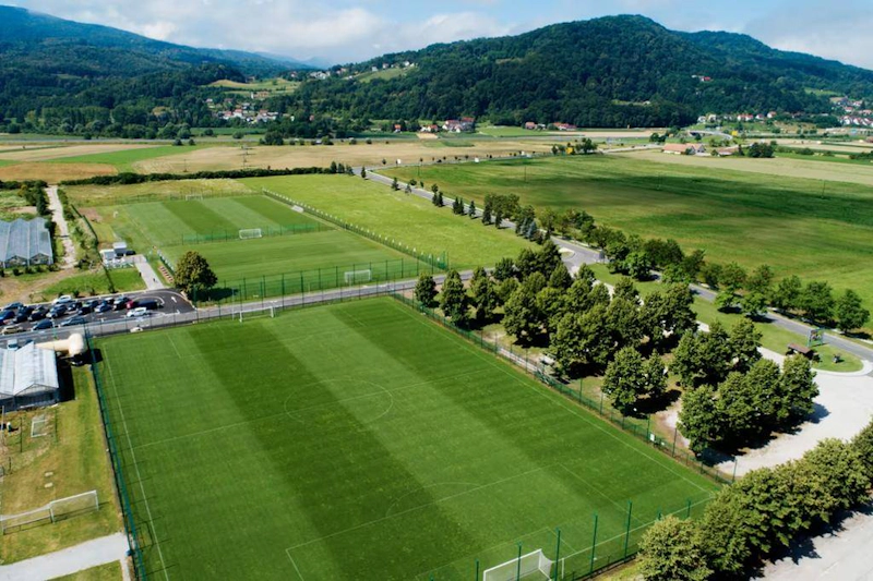 Football fields at Grand Prix Čatež Summer Trophy tournament surrounded by trees with mountains in the background.