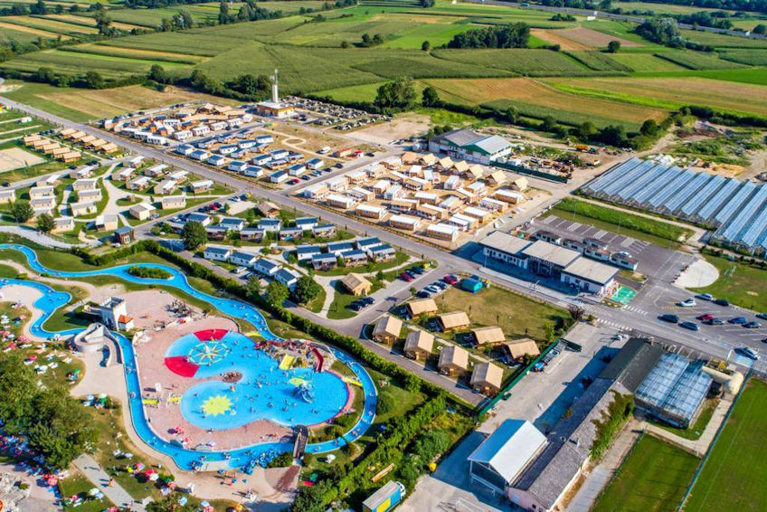 View of the Čatež resort with a pool and football field surrounded by green fields, Slovenia.