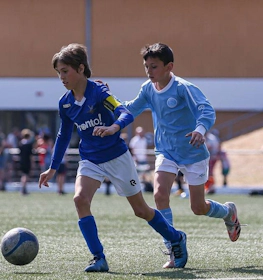 Mecz piłki nożnej na turnieju Hermes DVS International Youth Cup, dwóch młodych zawodników walczy o piłkę.
