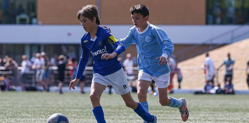 Mecz piłki nożnej na turnieju Hermes DVS International Youth Cup, dwóch młodych zawodników walczy o piłkę.