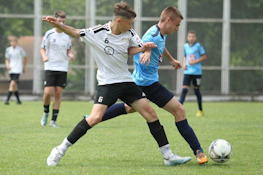 Meci de fotbal la turneul Sofia Summer Cup, doi jucători se luptă pentru minge.
