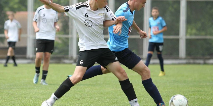 Meci de fotbal la turneul Sofia Summer Cup, doi jucători se luptă pentru minge.