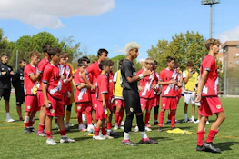 Drużyna piłkarska w czerwonych strojach na turnieju U15 Madrid Youth Cup Summer, młodzi zawodnicy przygotowują się do meczu.