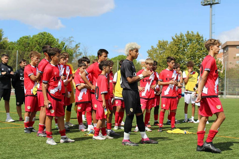 Equipo de fútbol con uniforme rojo en el torneo U15 Madrid Youth Cup Summer, jugadores jóvenes preparándose para el partido.