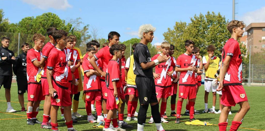 यू15 मैड्रिड यूथ कप समर टूर्नामेंट में लाल यूनिफॉर्म वाली फुटबॉल टीम, युवा खिलाड़ी मैच की तैयारी कर रहे हैं।