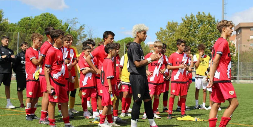 Echipa de fotbal în uniforme roșii la turneul U15 Madrid Youth Cup Summer, jucători tineri se pregătesc pentru meci.