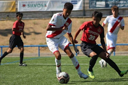 Match de football au tournoi U18 Madrid Youth Cup Summer, joueurs en uniformes rouges et blancs se disputant le ballon.