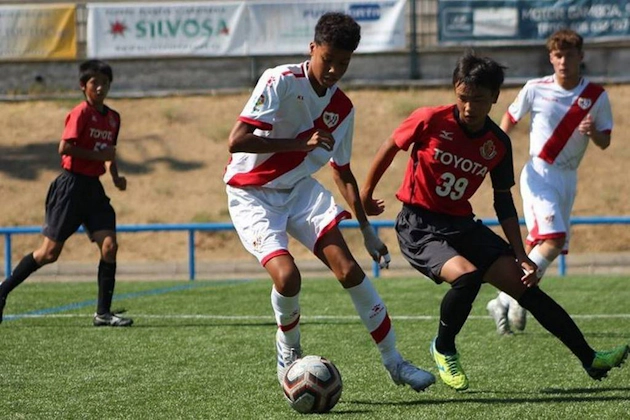 यू18 मैड्रिड यूथ कप समर टूर्नामेंट में फुटबॉल मैच, लाल और सफेद यूनिफॉर्म में खिलाड़ी गेंद के लिए प्रतिस्पर्धा कर रहे हैं।