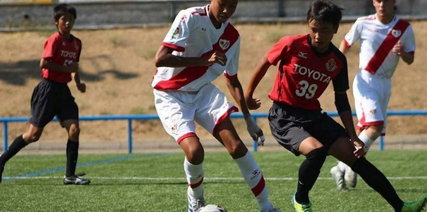 Fotballkamp på U18 Madrid Youth Cup Summer-turneringen, spillere i røde og hvite uniformer som kjemper om ballen.