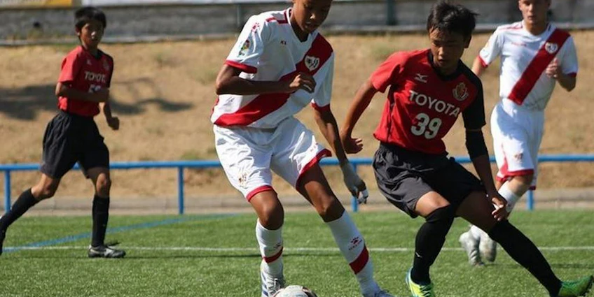Jalkapallo-ottelu U18 Madrid Youth Cup Summer -turnauksessa, punaisen ja valkoisen peliasun pelaajat kilpailevat pallosta.