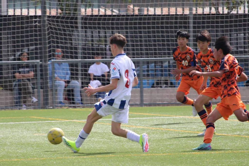 Игроки борются за мяч на поле во время летнего футбольного турнира U18 Madrid Youth Cup.