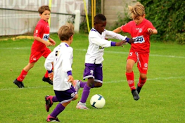 Fußballspiel beim Dufour International Cup Turnier, Spieler in weißen und roten Uniformen kämpfen um den Ball.