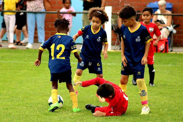 Παιδιά που παίζουν ποδόσφαιρο στο Dufour International Cup σε πράσινο γήπεδο