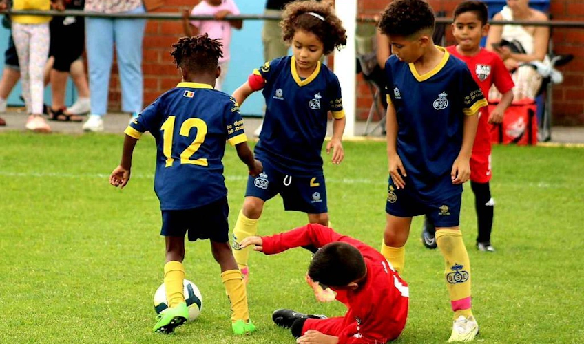 Dzieci grające w piłkę nożną na turnieju Dufour International Cup na zielonym boisku