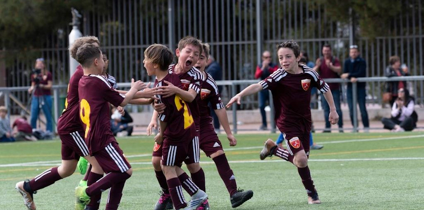 Young soccer players celebrating a goal at the Madrid Youth Cup Summer tournament